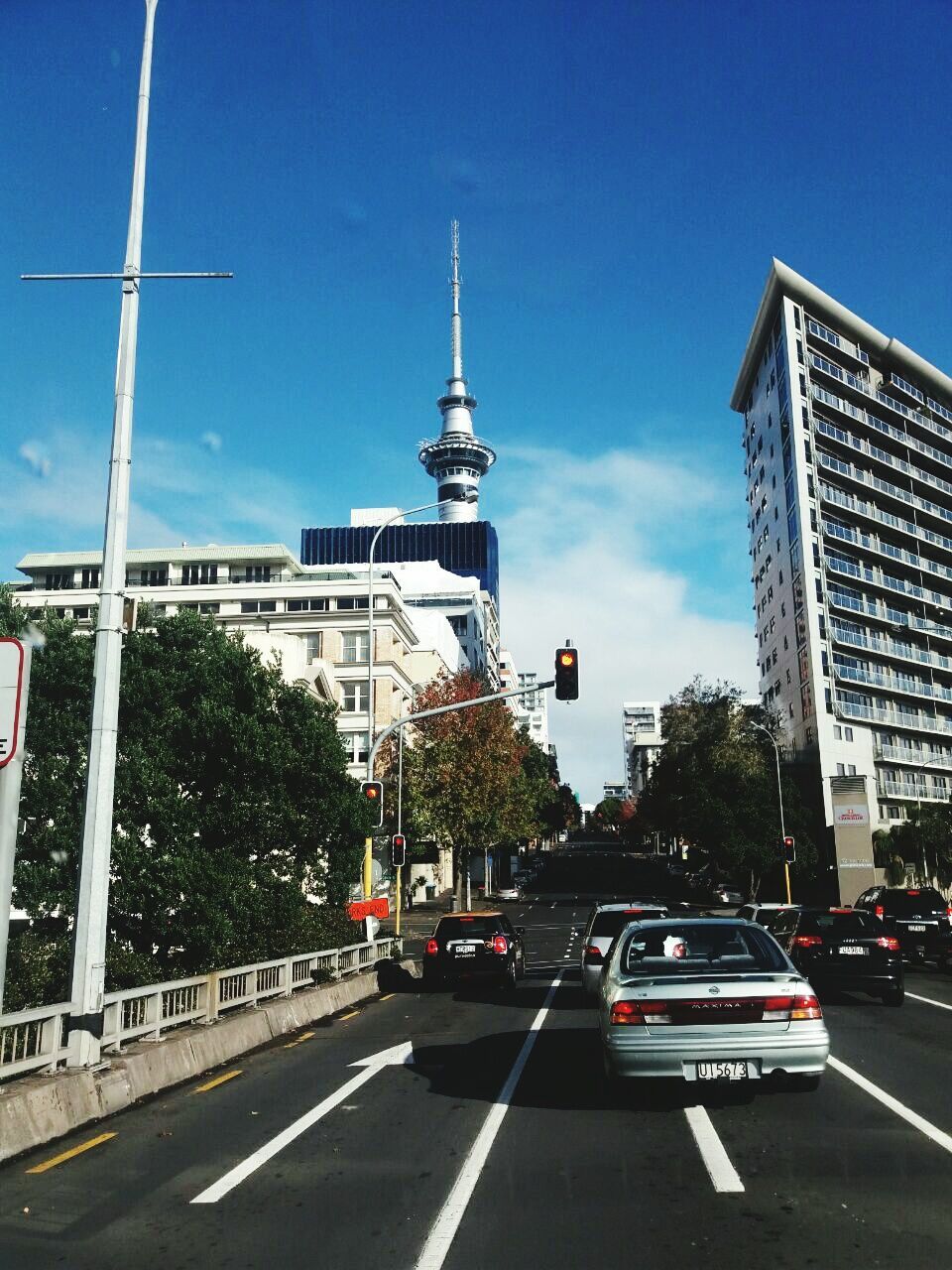 transportation, architecture, city, car, building exterior, built structure, land vehicle, tower, sky, road, mode of transport, outdoors, day, travel destinations, no people, skyscraper, road sign, tree