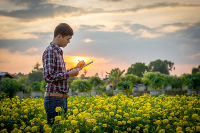 Man standing on field against sky during sunset