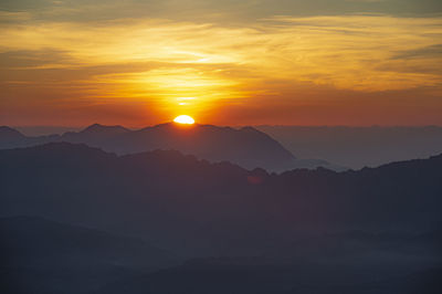 Scenic view of silhouette mountains against orange sky