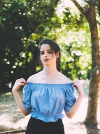 Young woman standing against trees