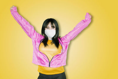 Portrait of woman standing against yellow wall