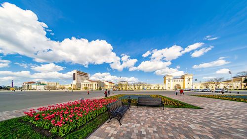 View of flowering plants by building against cloudy sky