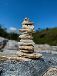 Stack of stones on rock against sky