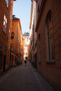 Rear view of people walking on narrow street amidst buildings