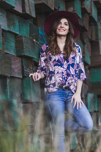 Portrait of smiling young woman standing against wall