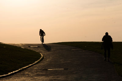 Rear view of man riding on road against sky