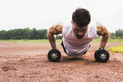 Athlete doing pushups with dumbbells on sports field