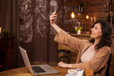 Portrait of young woman using mobile phone at table