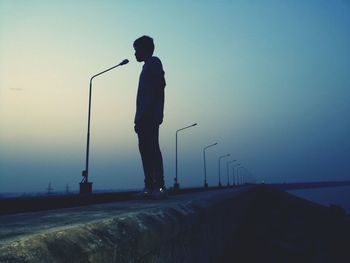 Silhouette of man standing on street light