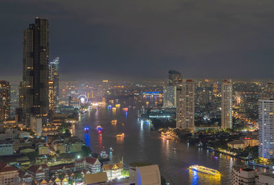 Illuminated modern buildings in city against sky at night