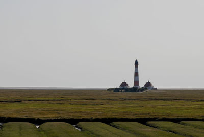 Lighthouse on field against clear sky