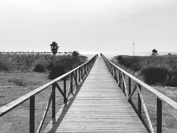 Footbridge on footpath against clear sky