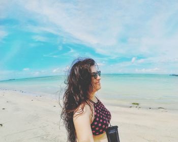 Beautiful woman standing on beach against sky