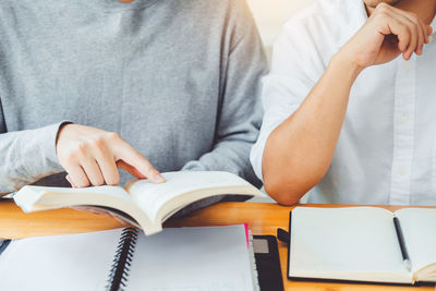 Midsection of man reading book on table
