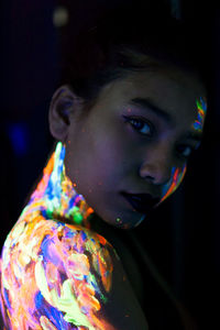 Close-up portrait of young woman with paint on face and shoulder