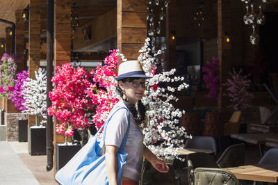 Portrait of woman standing by potted plants