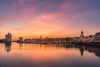 Panoramic view of the old harbor of la rochelle at sunset with its old towers. beautiful orange sky