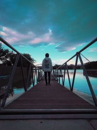 Rear view of man standing on pier against sky