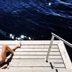 Low section of a woman lying on wood paneled surface by the sea