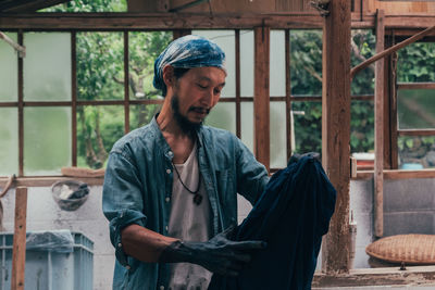 Man holding clothing while standing in shed