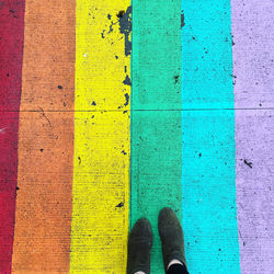 Low section of person standing by multi colored shoes