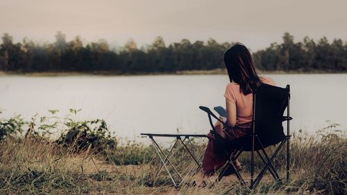 Low section of woman standing by lake