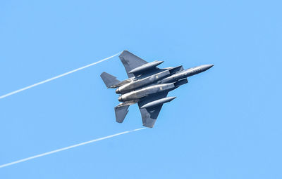 Low angle view of airplane flying against clear blue sky