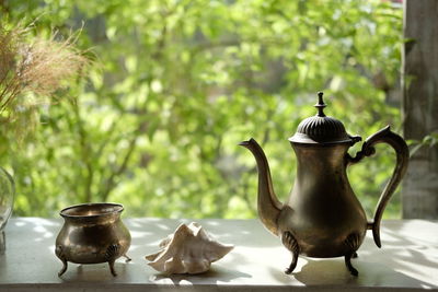 Close-up of tea kettle on table against window