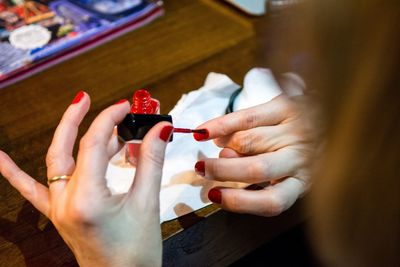 Cropped hands of woman applying red nail polish