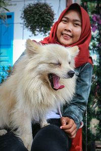 Young woman holding dog while sitting outdoors