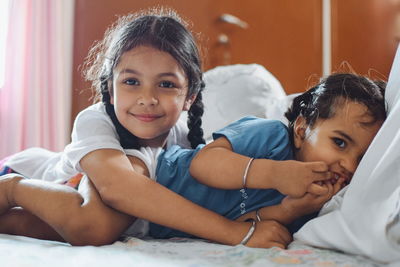 Portrait of happy friends sitting on bed at home