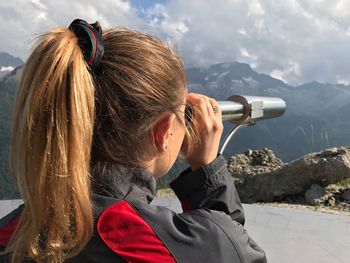 Rear view of woman looking through telescope against mountains