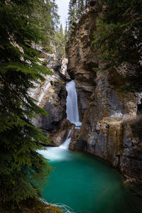 A stream of water cuts through the rock shelves in johnston canyon.