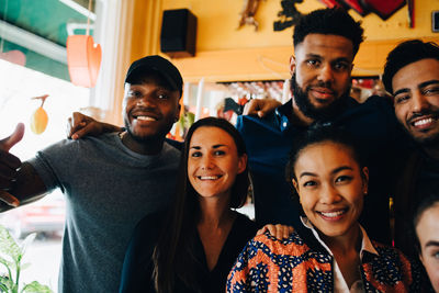 Portrait of smiling young multi-ethnic friends while standing in restaurant during brunch
