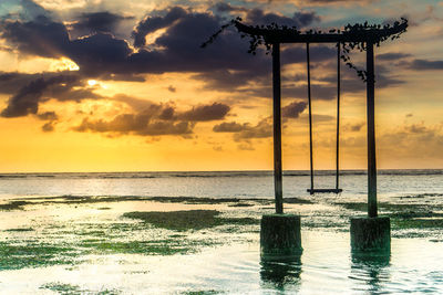 Scenic view of swing by sea against sky during sunset