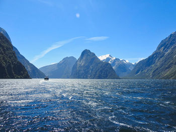 Scenic view of sea and mountains against blue sky