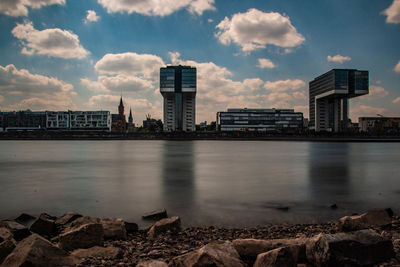 Buildings by river against sky in city