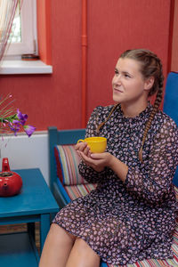 Cheerful girl drinks coffee from a yellow mug.