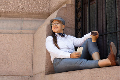 Full length of young woman sitting outdoors