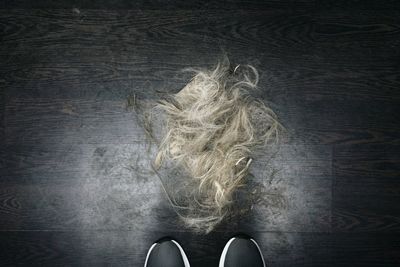 Low section of man standing by hair on floor