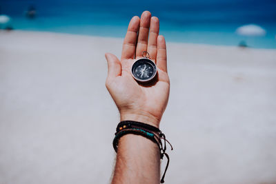 Low section of person holding ring at beach against sky