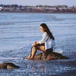 Portrait of smiling young woman sitting on beach