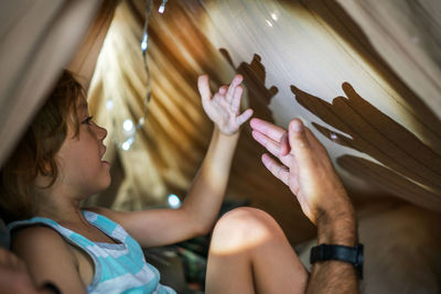 Portrait of a 6 year old boy and his father having fun playing in teepee tent.