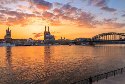 Bridge over river with city in background at sunset