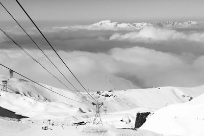 Electricity pylon on snowcapped mountains against sky