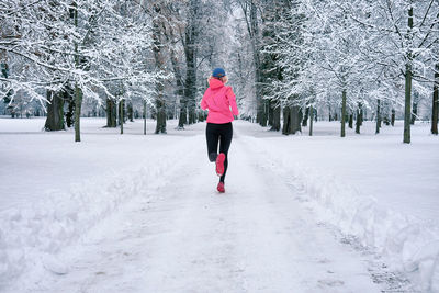 Rear view of woman walking on snow covered field