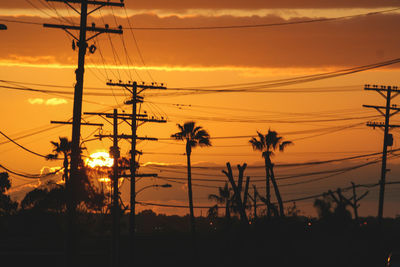 Silhouette electricity pylon against sky during sunset