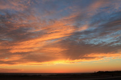 Scenic view of sea against cloudy sky at sunset