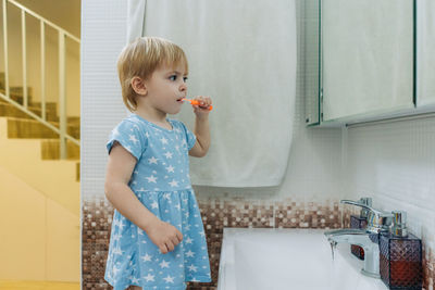 Little toddler girl brushes her teeth in the bathroom.