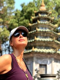 Woman looking away while standing against built structure